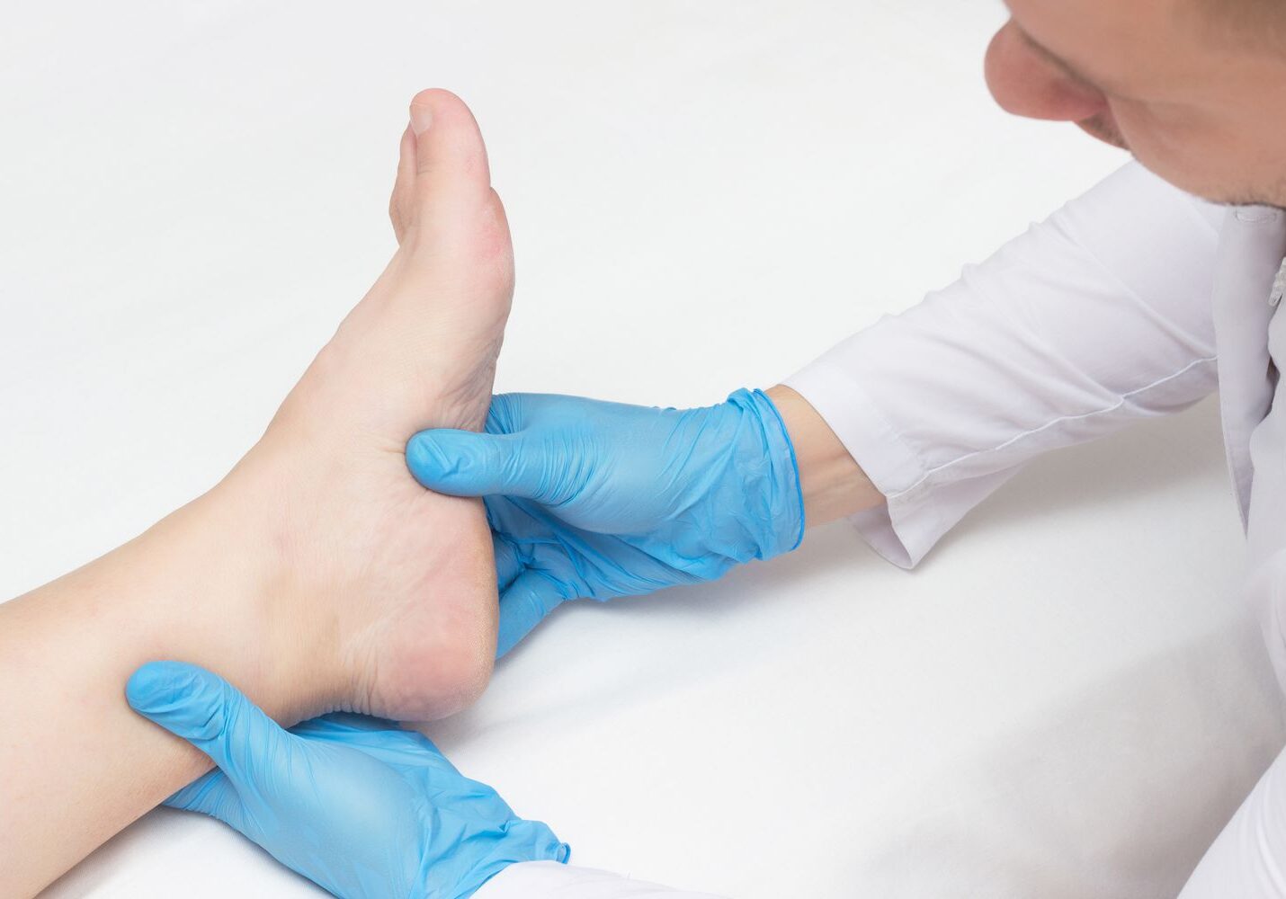 doctor-examines-the-patient-s-leg-with-heel-spurs--pain-in-the-foot--white-background--close-up--plantar-fasciitis-1174571272-cbdd17112bef4f67b022126ca117286c